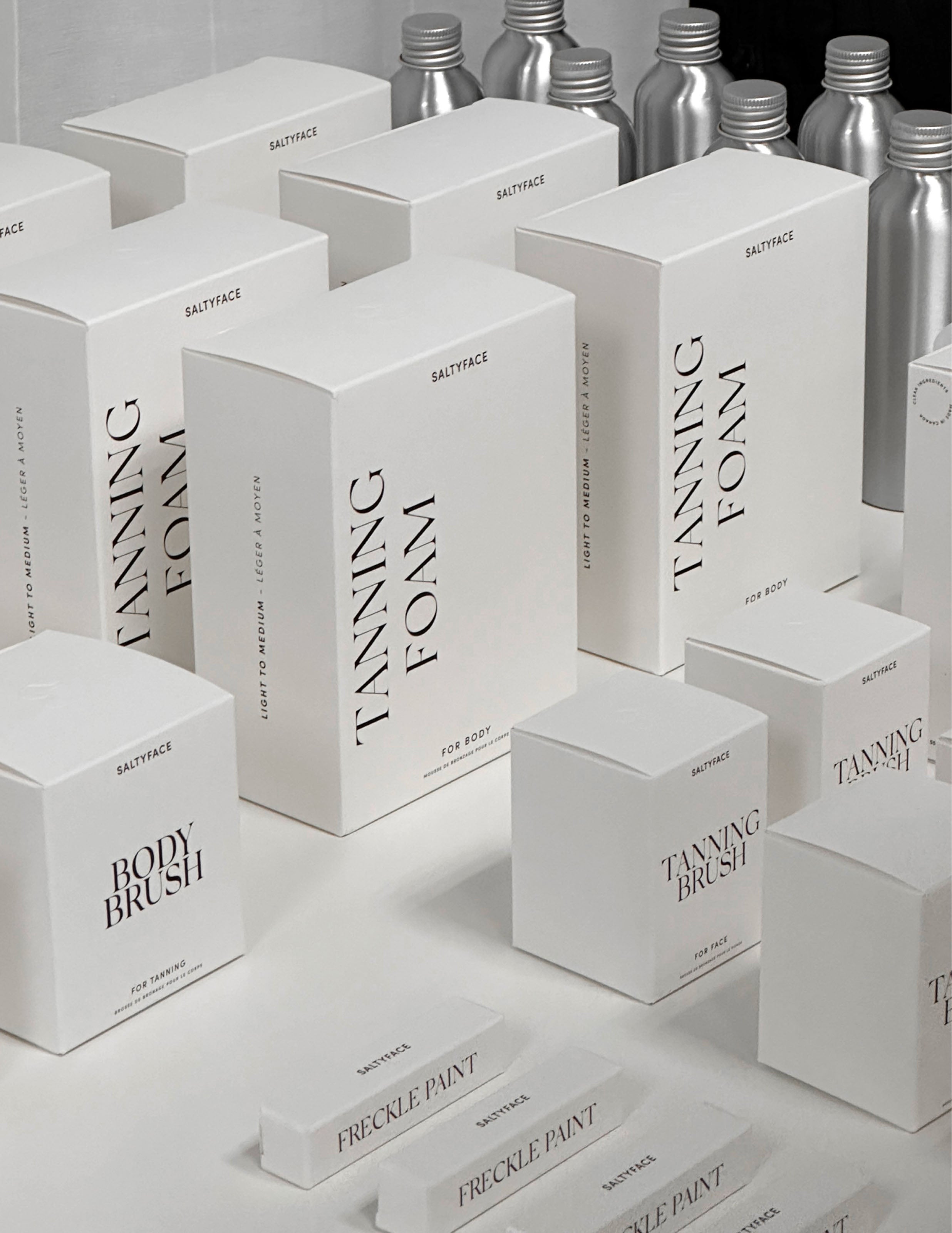 Assorted white boxes of Saltyface products are lined up on top of a white table.