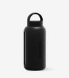 The Day Bottle, a black glass water bottle with a rounded cap, loop handle, and SALTYFACE label down the side, is shown against a plain white background—perfect for staying hydrated all summer.
