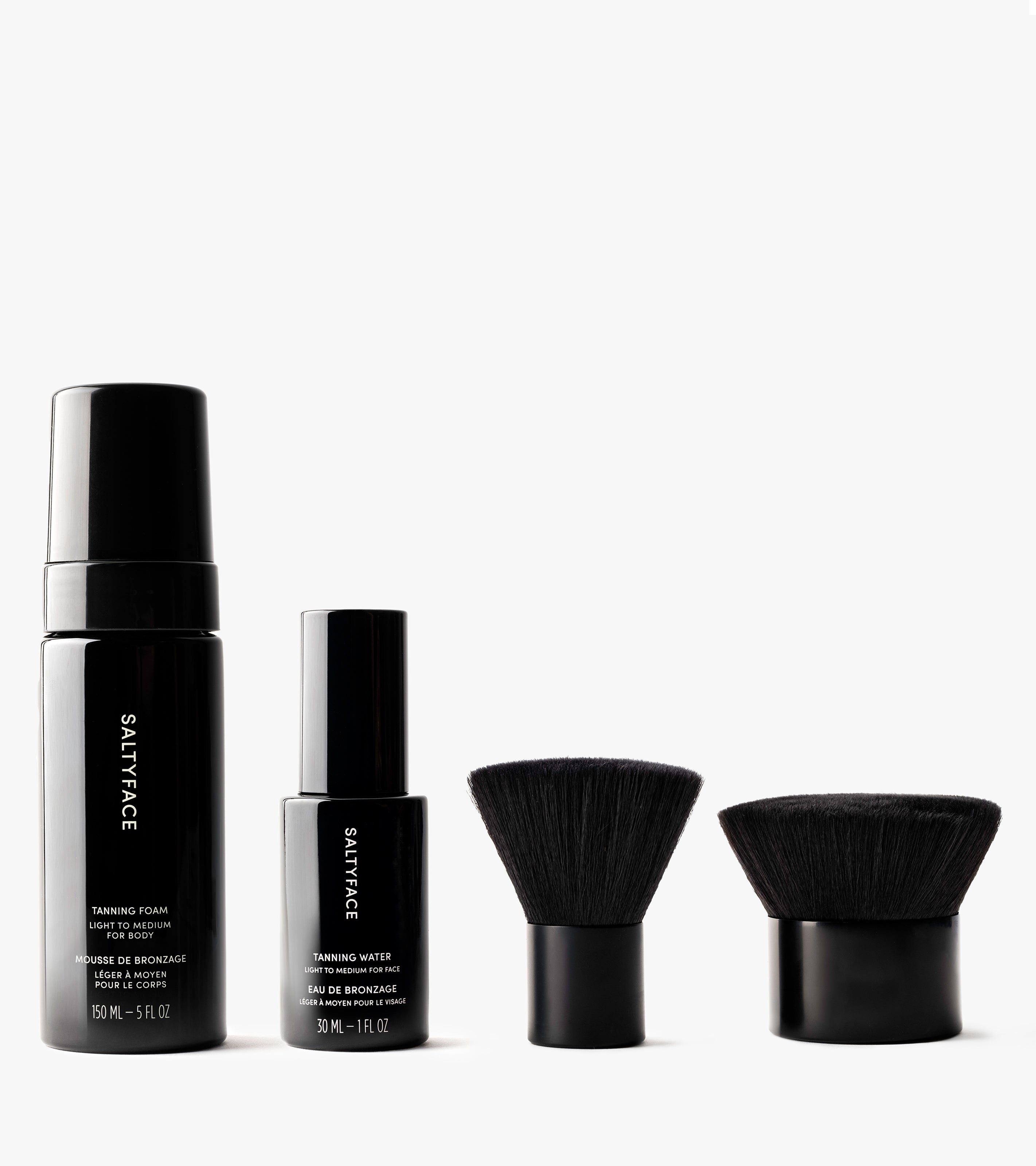 The Complete Face & Body Set—including tanning foam, a mini tanning water, and two dense flat brushes—is neatly displayed on a white background, creating the perfect kit for flawless application.