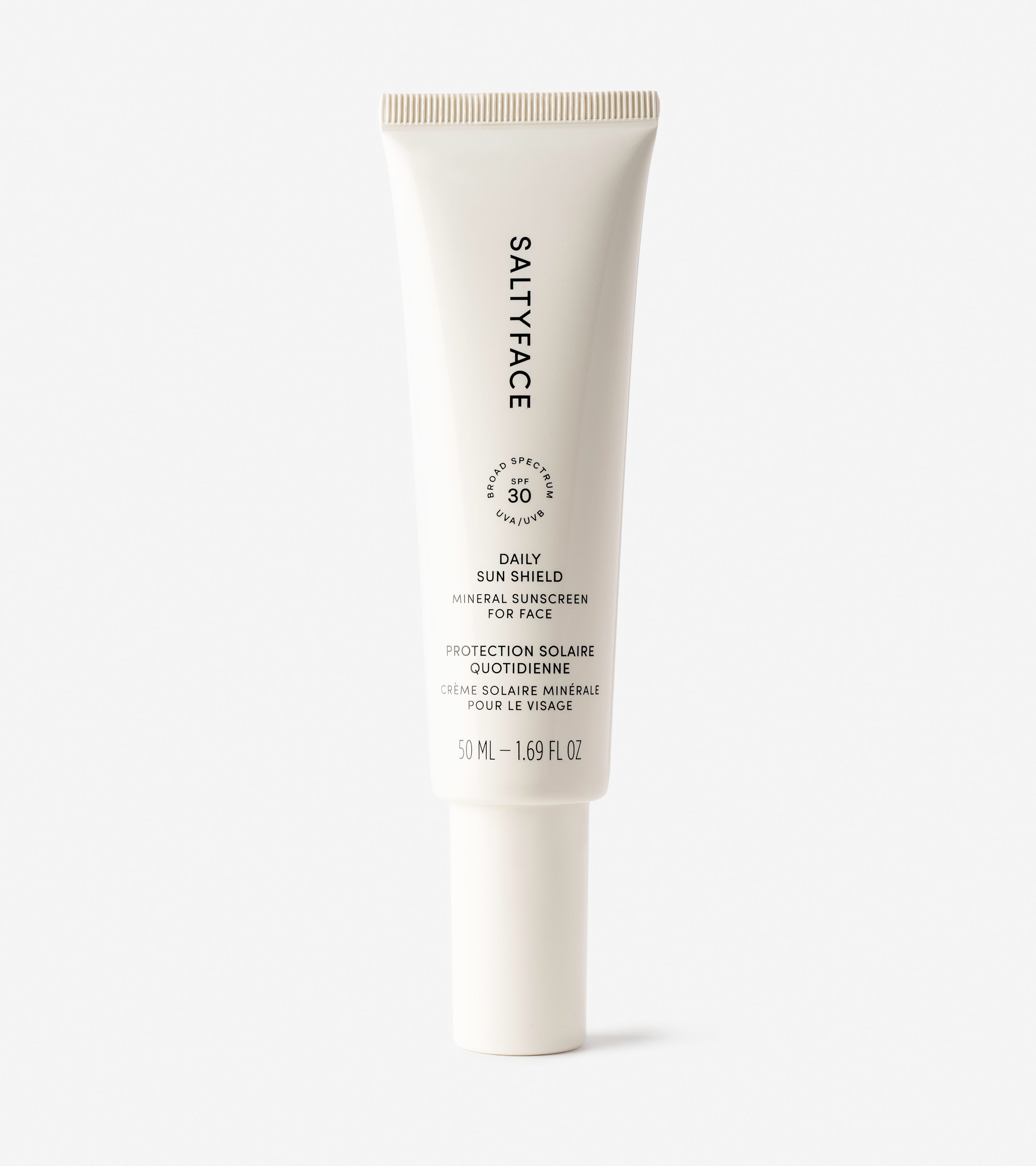 A white tube of Daily Sun Shield mineral SPF 30 sunscreen, with black text and a minimalist design, stands upright on a plain white background.