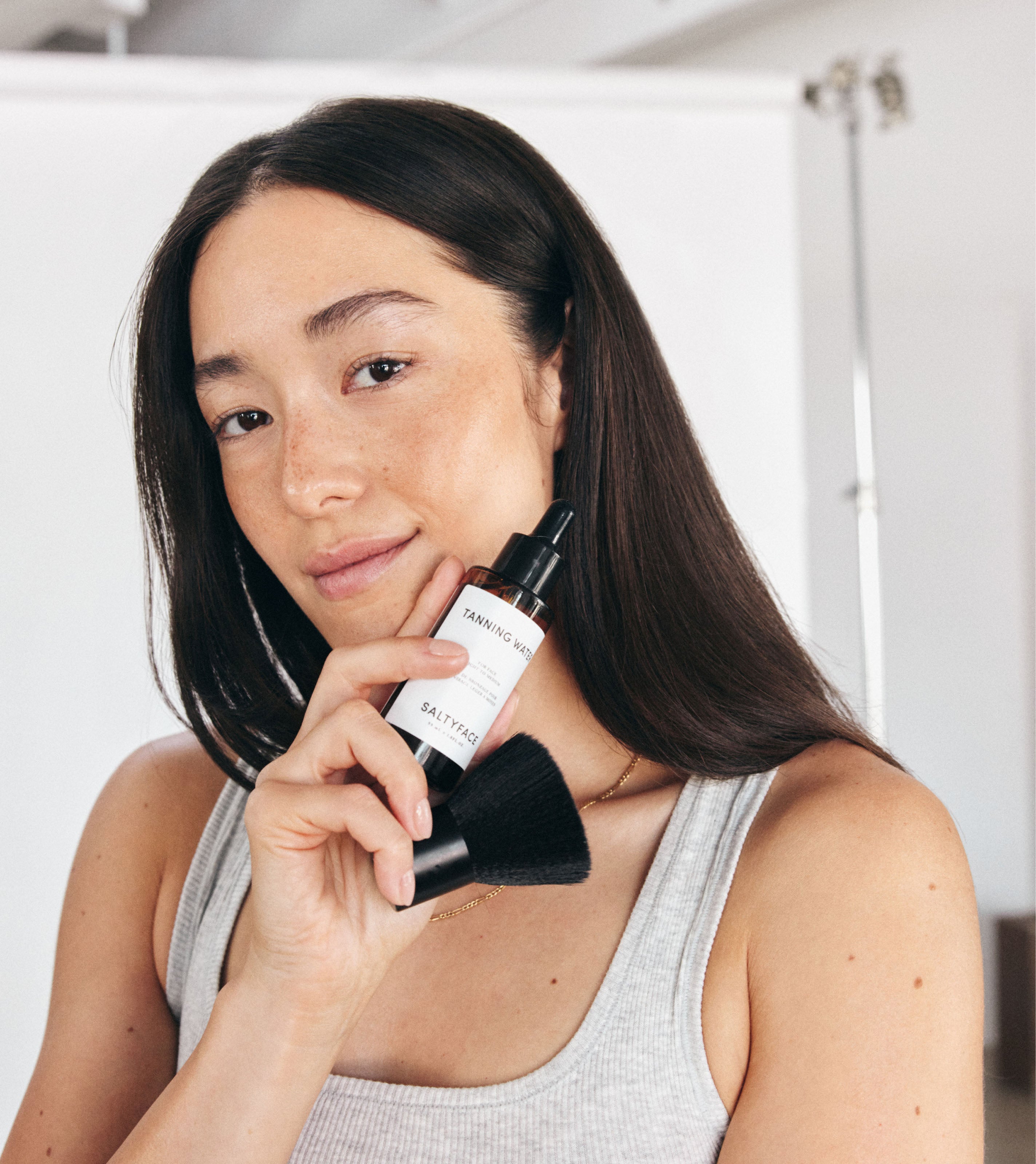 Model holding Saltyface Tanning Water and Brush No. 1.