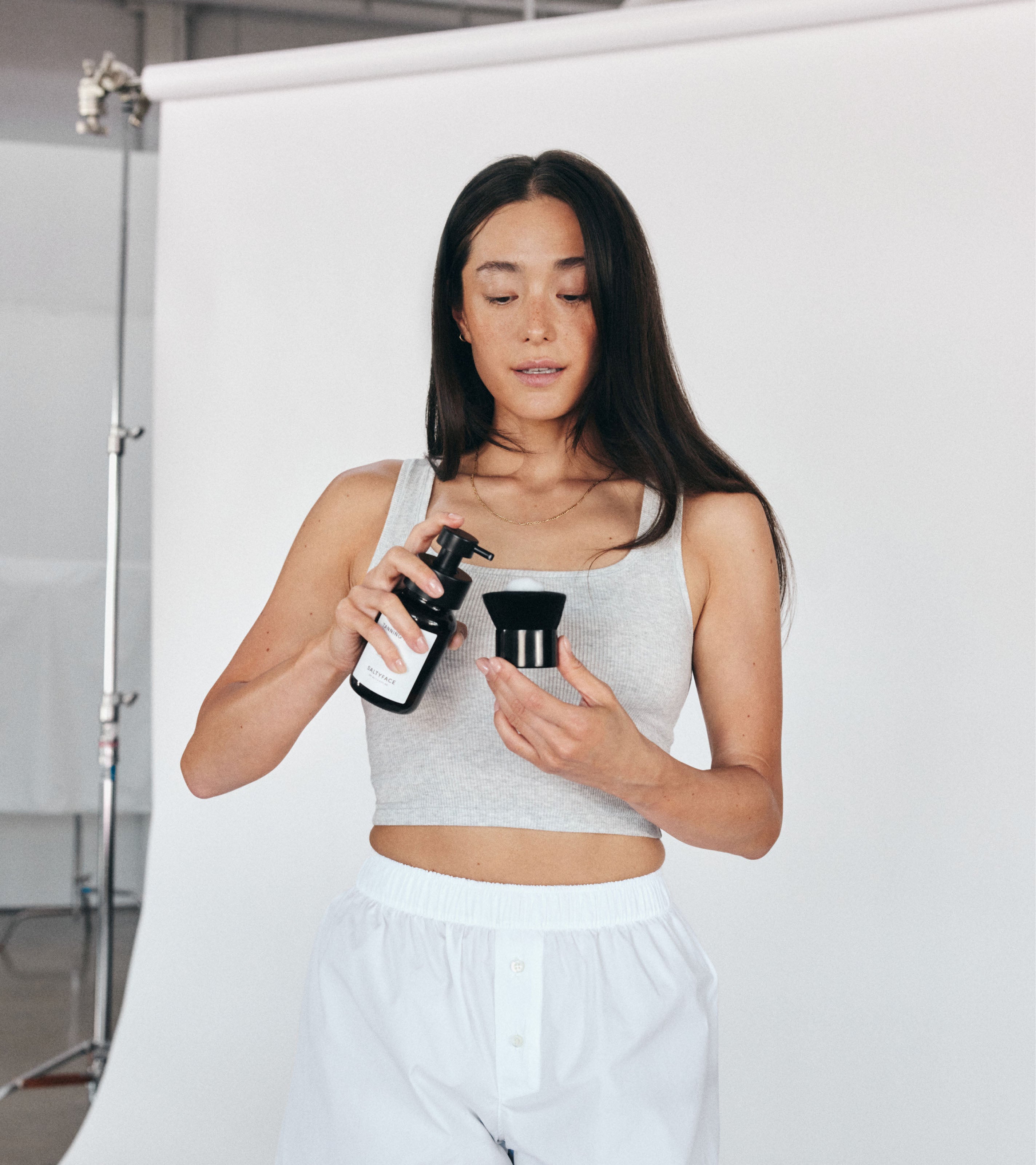 Model dispensing Saltyface Tanning Foam on to the Body Brush
