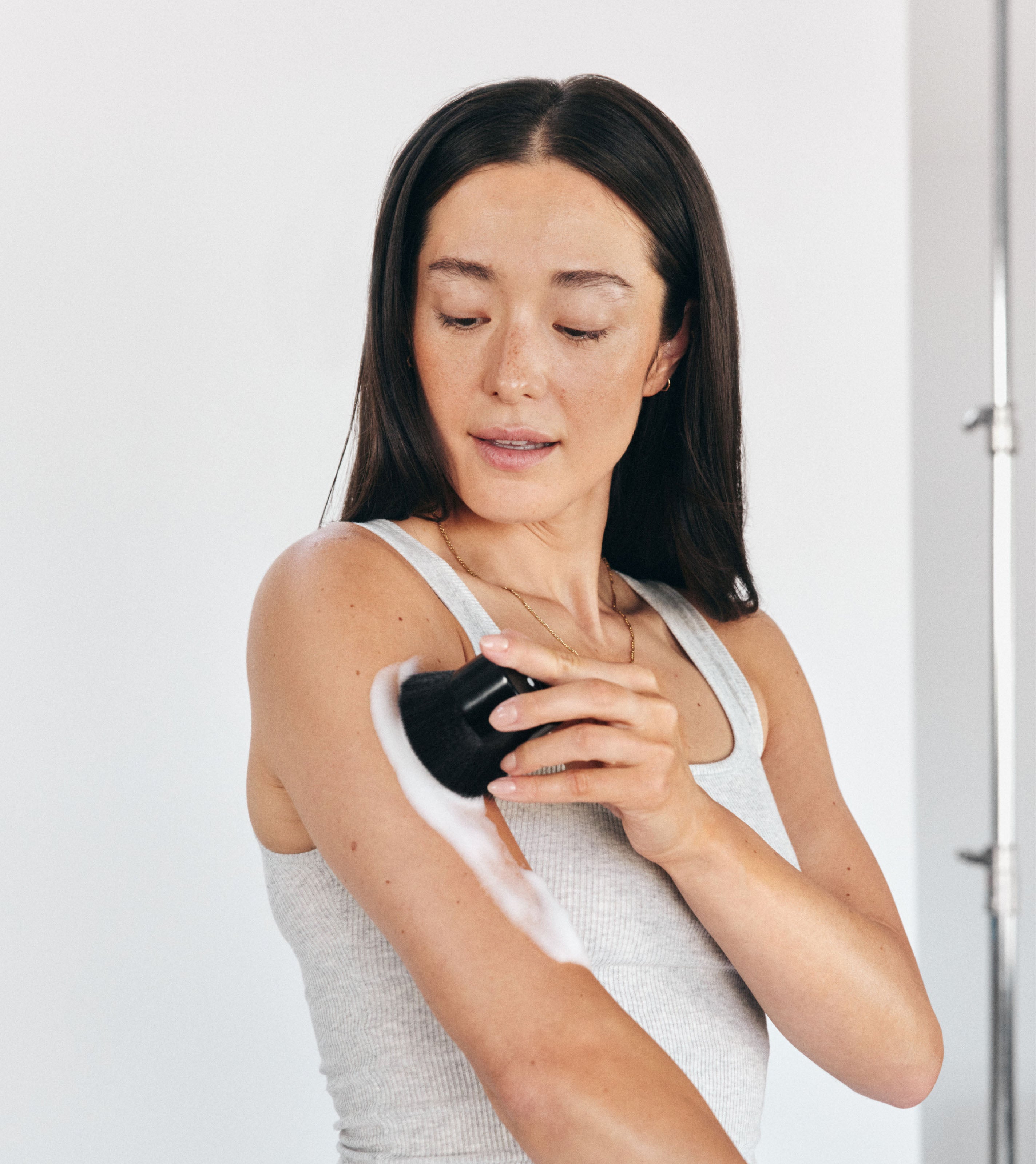 Model using Brush No. 2 to apply Saltyface Tanning Foam on her arm. 