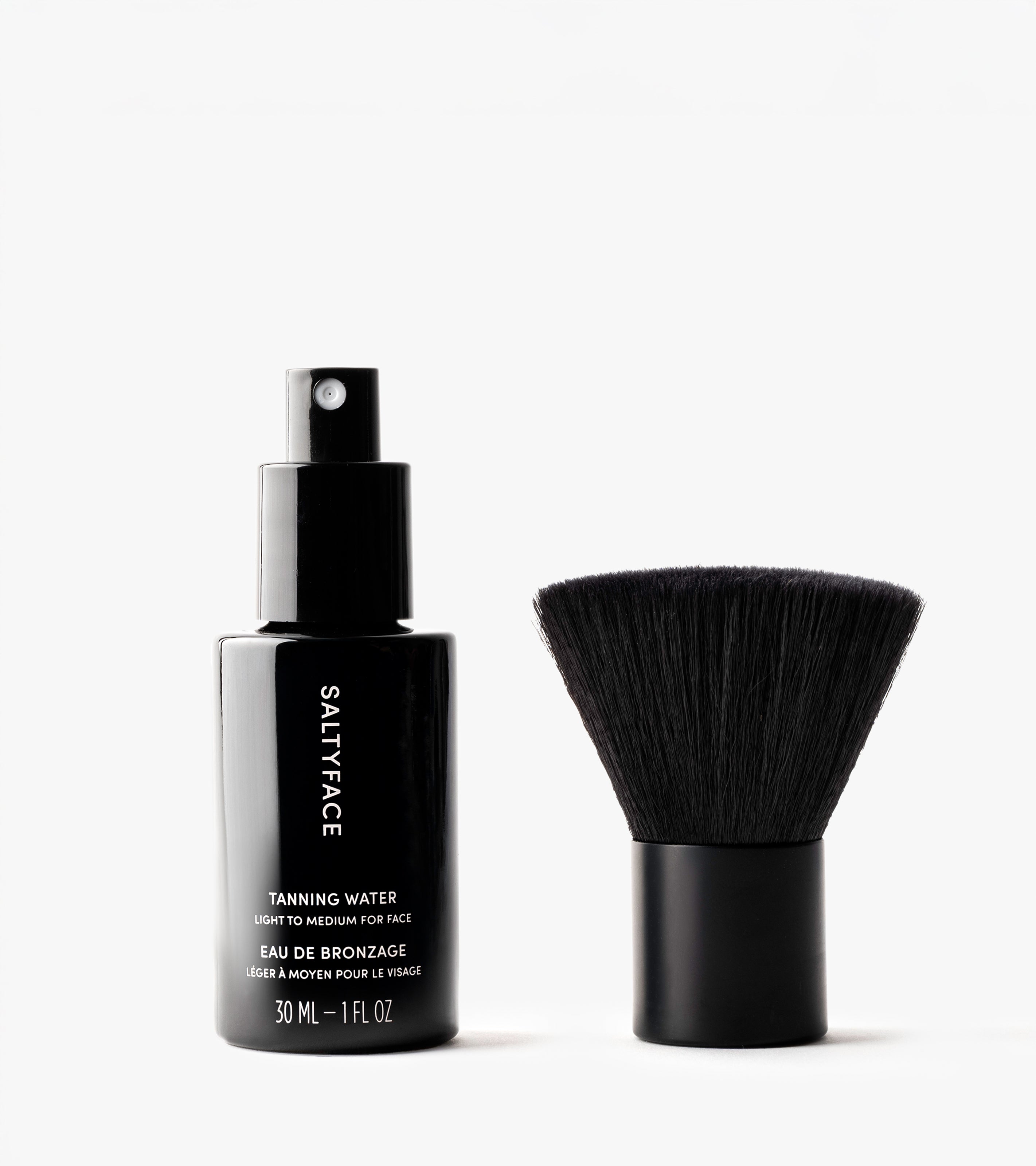 The Face Set, featuring a black Saltyface Tanning Water spray bottle and a short, wide face brush for an even tan, is displayed against a white background.