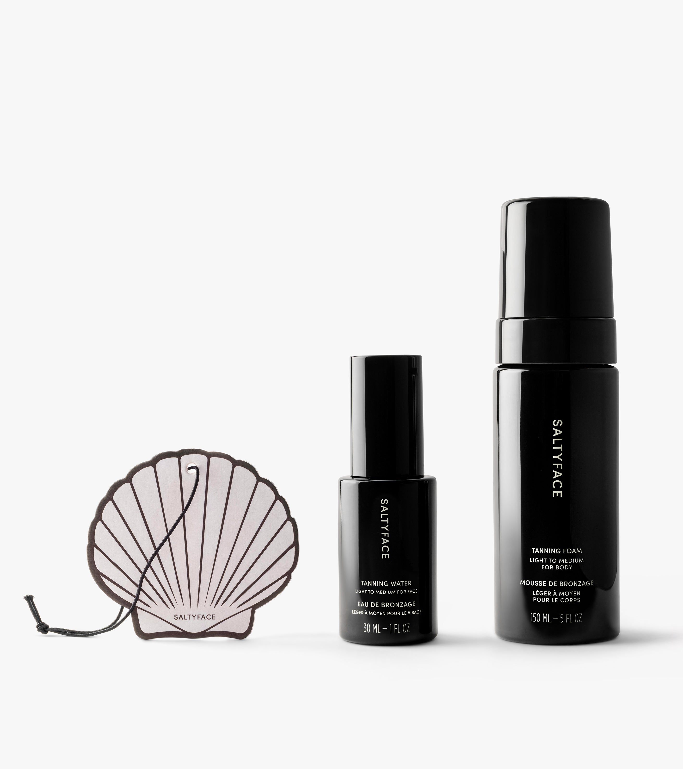 The Coconut Set includes three Saltyface products on a white background: a shell-shaped tanning applicator, a 30mL tanning water, and a 150mL tanning foam—all in sleek black packaging.