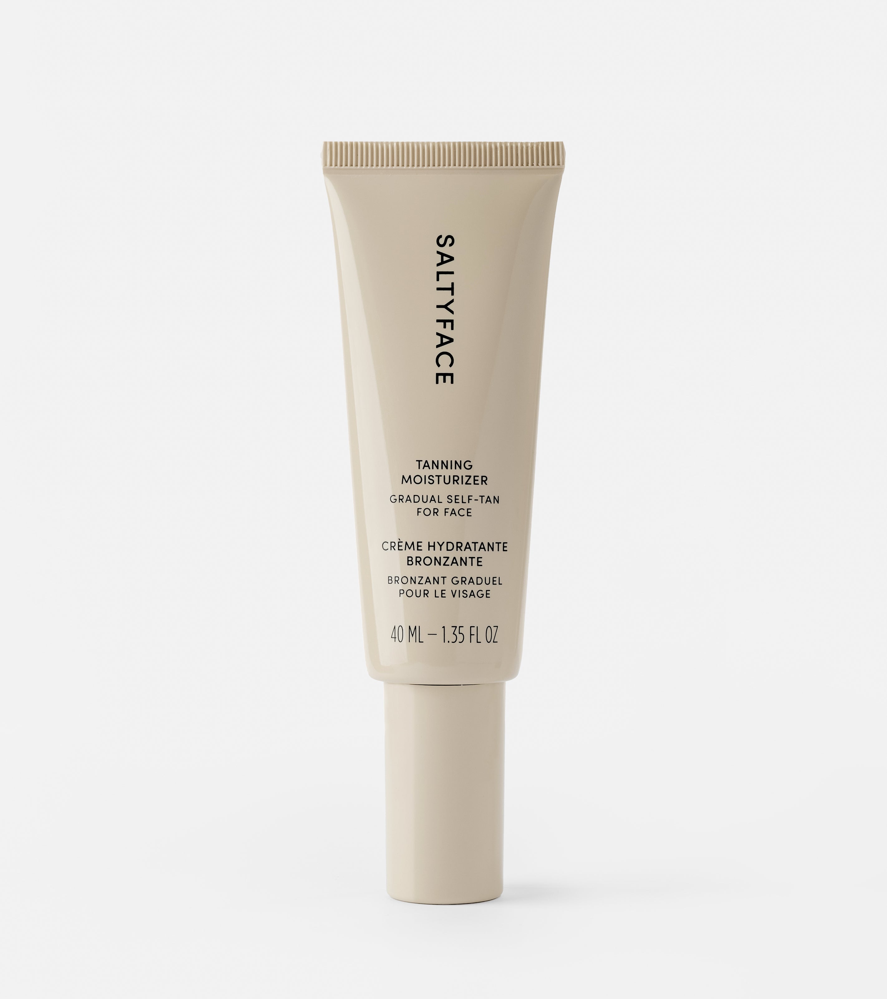 A beige 40 ml (1.35 fl oz) tube of SALTYFACE Tanning Moisturizer with English and French labels stands upright on a white background.