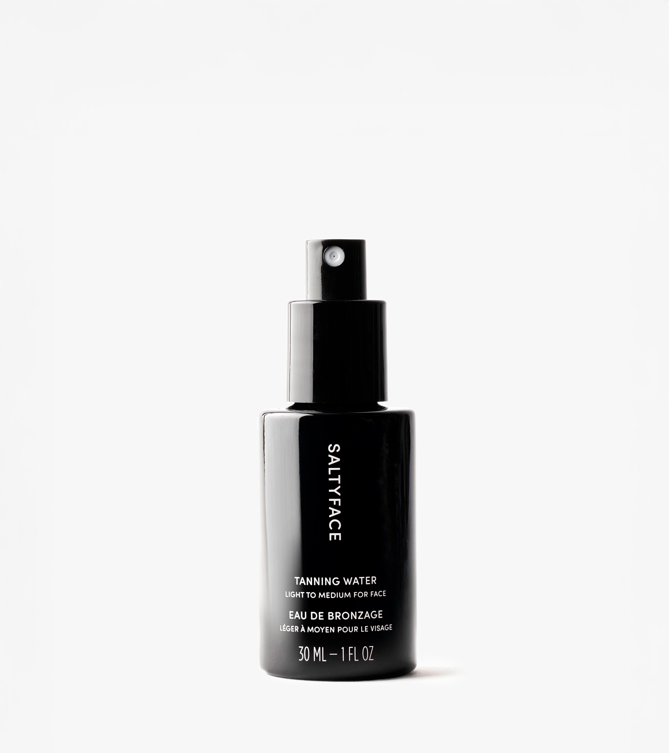 A black spray bottle labeled SALTYFACE Tanning Water stands upright on a white background. This award-winning 30 mL (1 fl oz) product delivers a natural, sun-kissed tan for light to medium skin tones.