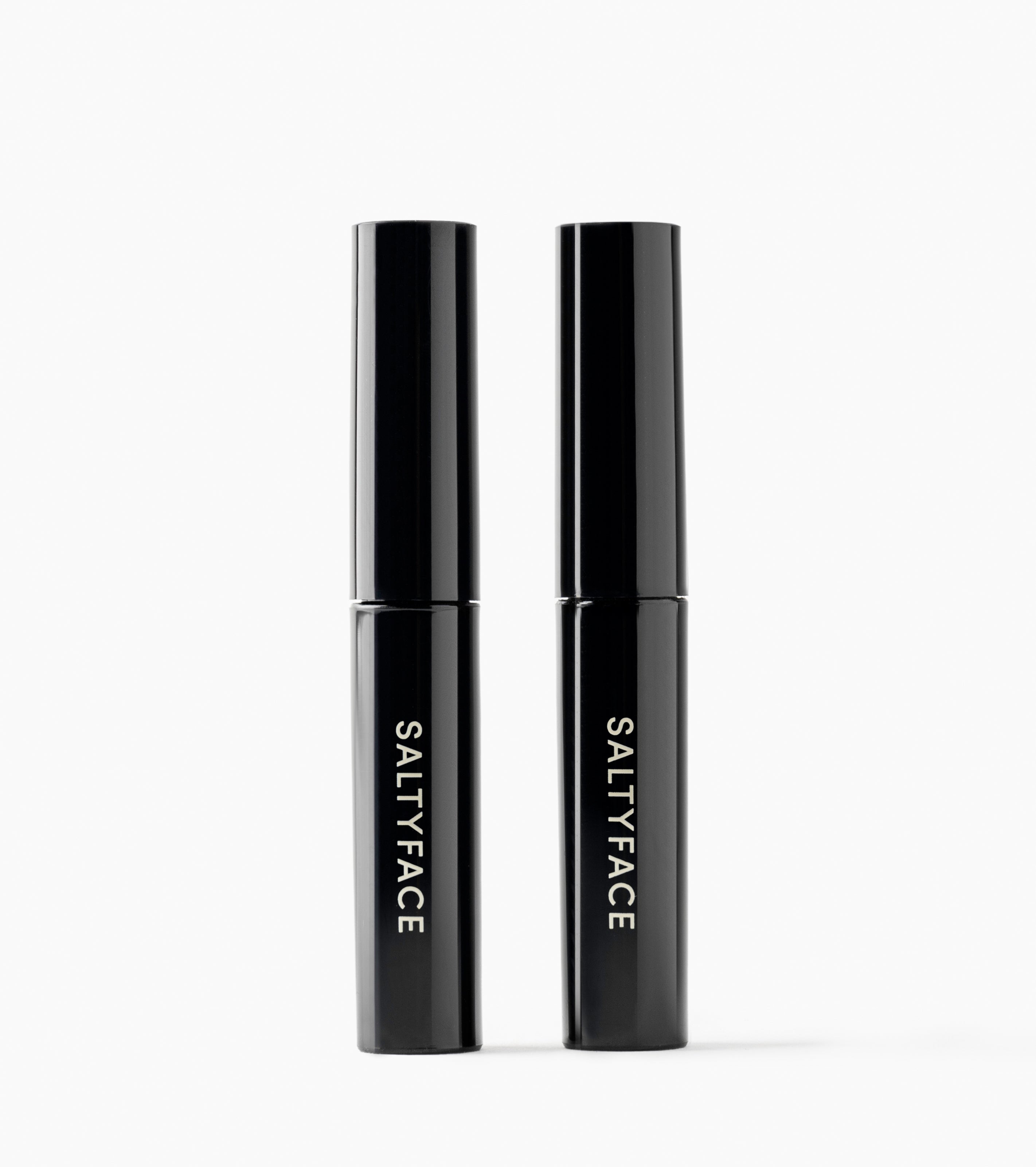 Two black cylindrical tubes labeled with "SALTYFACE" in white, stand side by side on a plain white background, showcasing The Stocking Stuffer Duo.