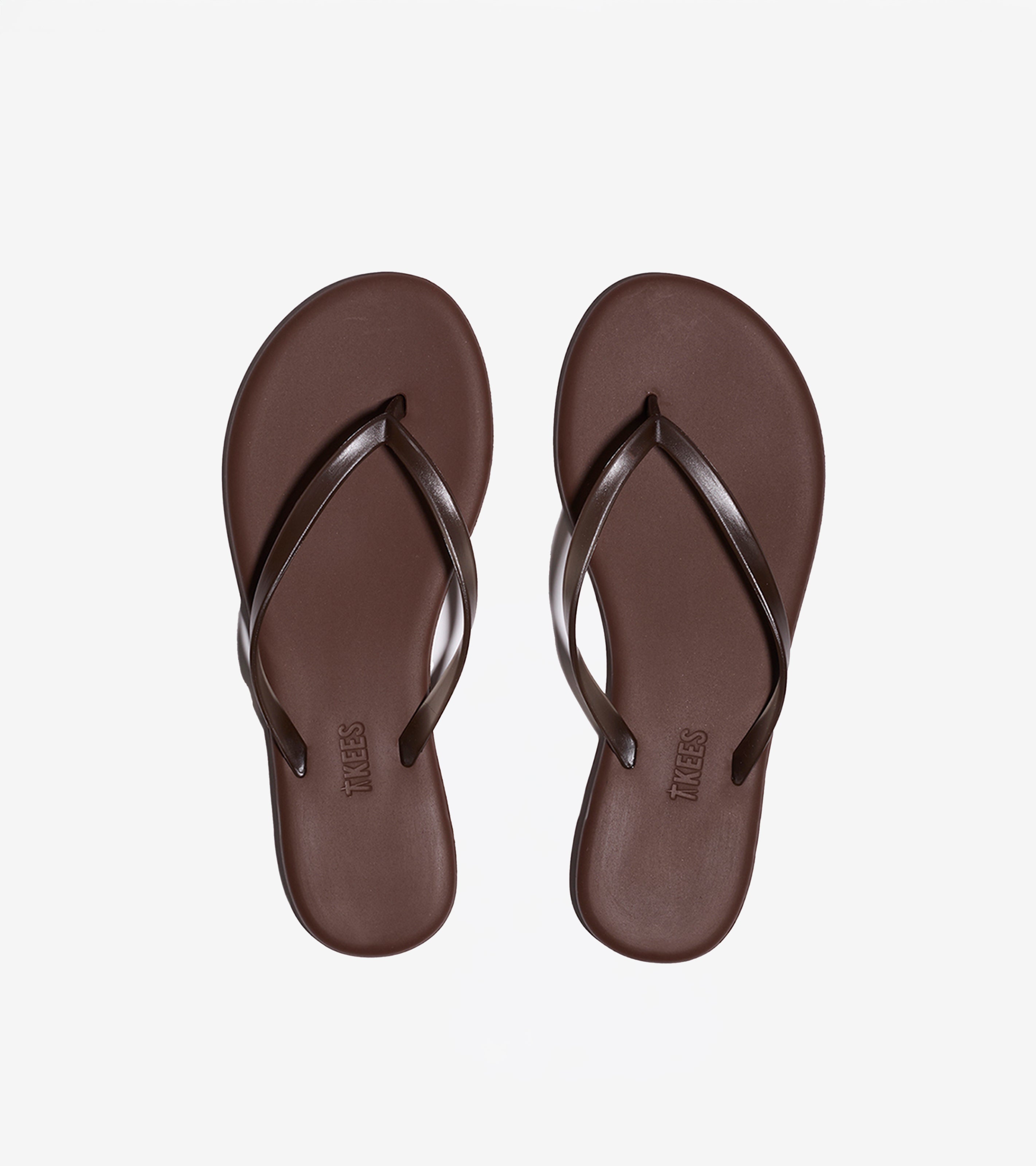 Aqua Flip Flops—stylish brown sandals with thin straps—are neatly placed side by side on a plain white background.