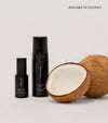 Three black bottles of The Saltyface Set are shown beside a whole and halved coconut, promoting viral best-sellers for a natural sun-kissed glow. "AVAILABLE IN COCONUT" appears in the top right on a neutral background.