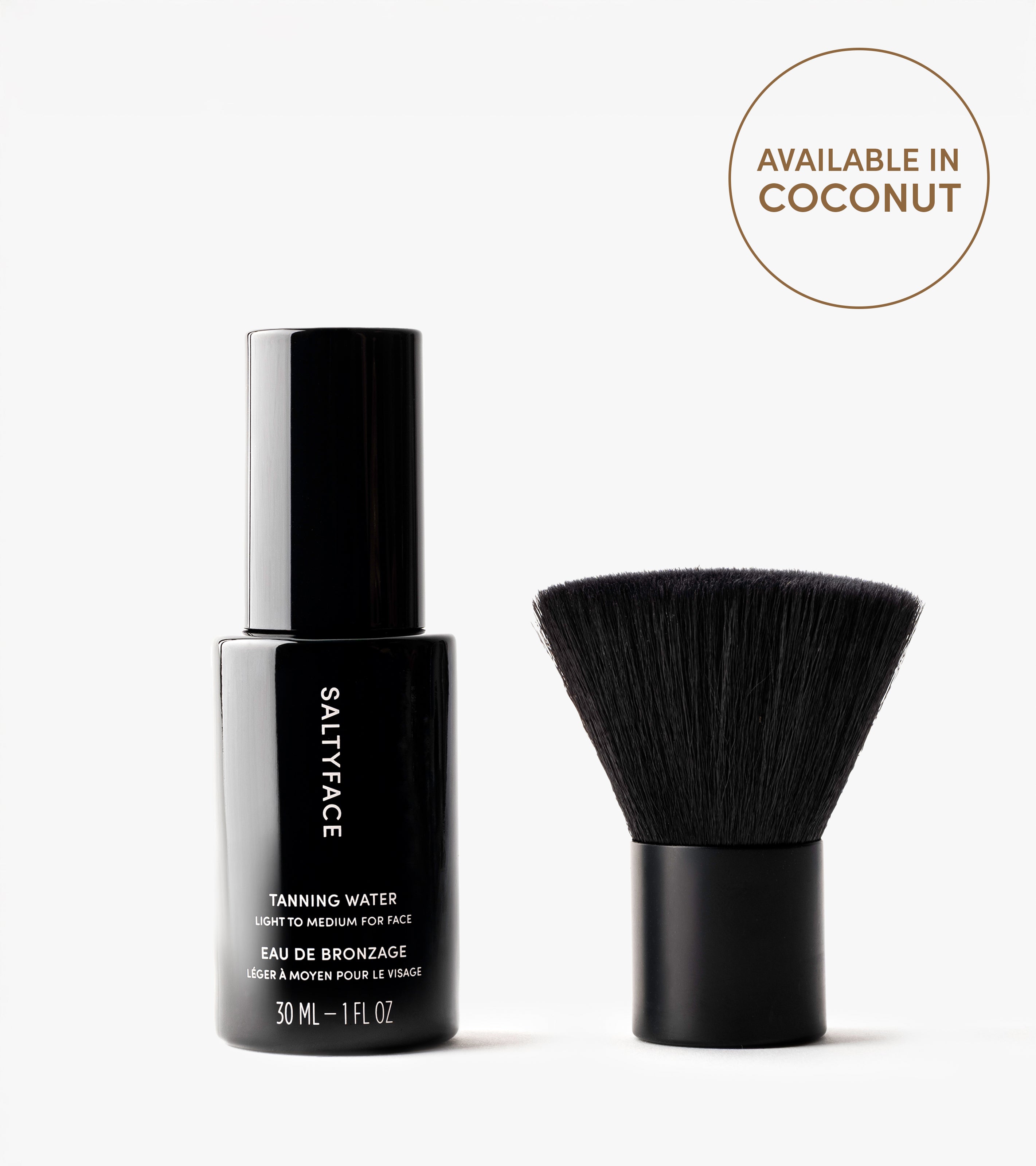 A black bottle labeled The Face Set stands next to a short, wide face brush with black bristles. A circle on the right reads, Available in Coconut. Perfect for achieving a flawless face tan on a white background.