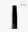 A black bottle of Tanning Foam (Light to Medium) is shown on a white background, offering a coconut scent and water-to-foam formula for easy self tanning. This body care product comes in a 150 mL (5 fl oz) size.