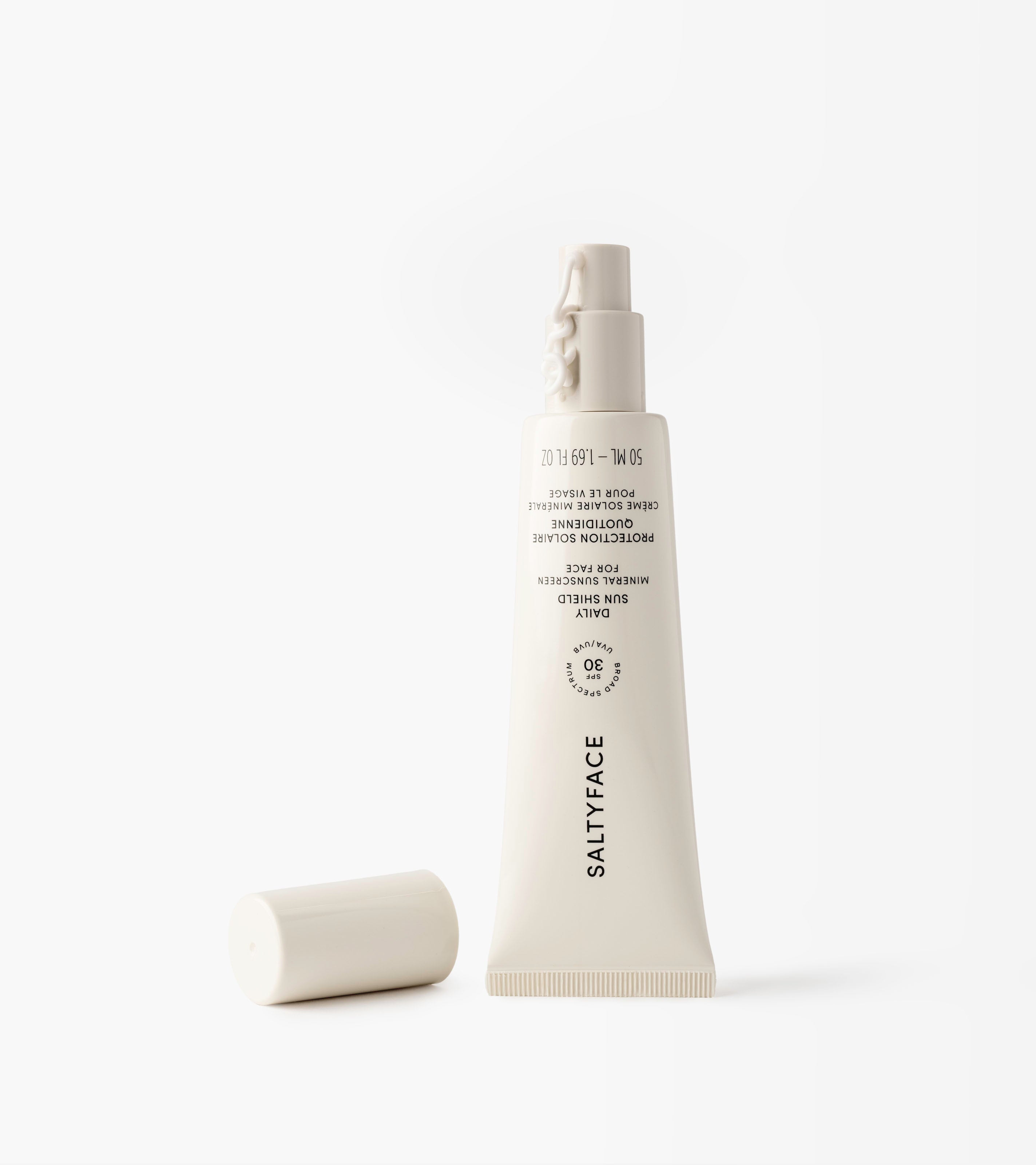 A white tube of Daily Sun Shield mineral sunscreen SPF 30 rests on its side with the cap off, set against a plain white background.