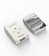 A white box labeled SALTYFACE with card suit symbols sits next to a stack of Playing Cards; the top card features a black-and-white ocean wave photo.