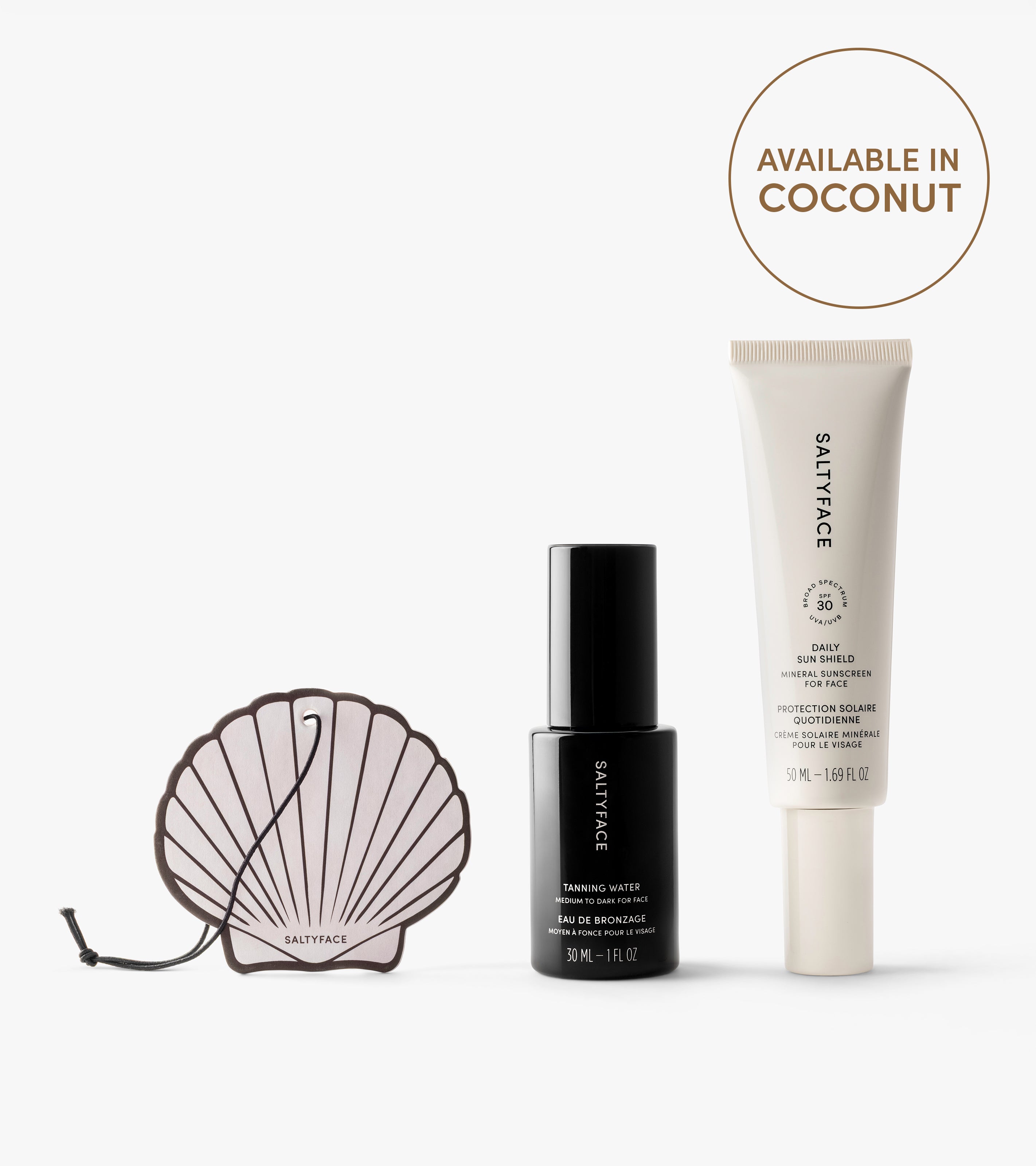 The Sun Set by Saltyface includes a shell-shaped tanning water applicator, a black tanning water bottle, and a white daily skin shield SPF 30 tube. A circular label indicates it's available in Coconut.